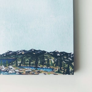 May include: A landscape painting featuring a mountain range with snow-capped peaks, lush green forests, and a serene blue lake. The artwork has a light blue sky and a detailed depiction of trees and rocks.