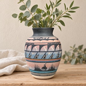 May include: A ceramic vase featuring a matte finish with a multi-coloured horizontal band design. The pattern includes black, pink, and blue geometric shapes, thin lines, and a silhouette of a horse and rider amidst trees near the base.