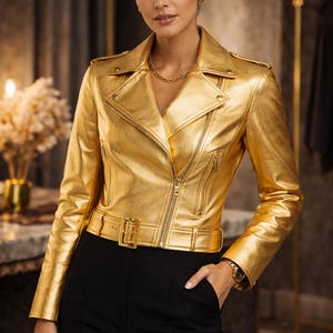 May include: A metallic gold biker jacket with a notched collar, asymmetrical zip closure, and a belted waist. The jacket features a shiny, textured finish and is paired with black pants. A gold chain necklace and watch complete the look.