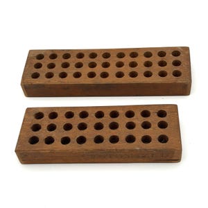 May include: Two rectangular brown wooden blocks, each featuring three rows of circular holes drilled into the top surface. The bottom block displays the word CUSTOMIZED embossed on its front side, showing a natural wood grain texture throughout.
