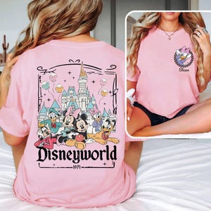 May include: A light pink t-shirt featuring a Disney World graphic on the back with Mickey, Minnie, Donald, Daisy, Goofy, and Pluto. The front has a small Daisy Duck graphic with the word "Sister".