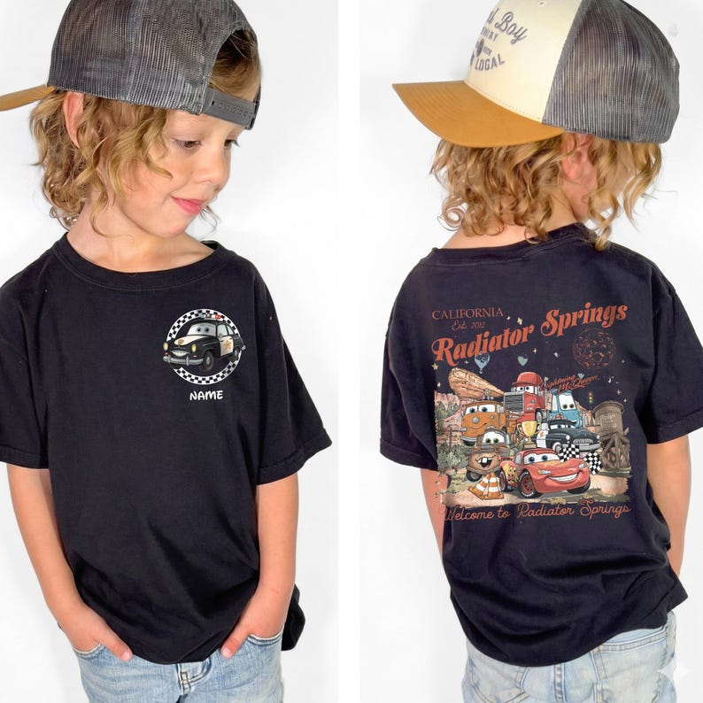 Puede incluir: Camiseta negra con un dise&ntilde;o de coche de polic&iacute;a de dibujos animados y la palabra "NAME". La parte trasera de la camiseta muestra un gr&aacute;fico colorido de personajes y el texto "Radiator Springs, California".