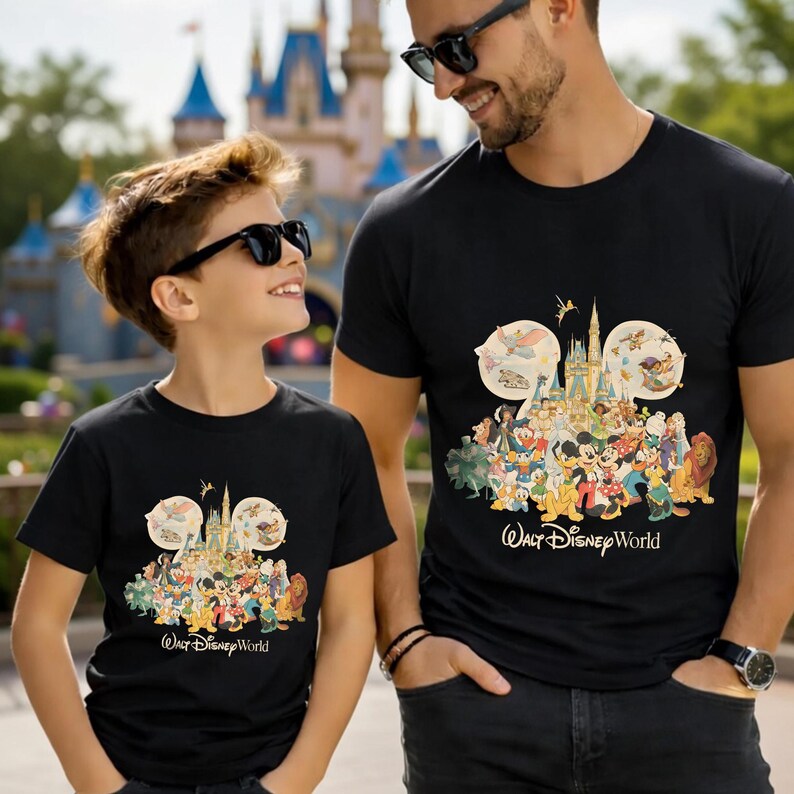 Puede incluir: Camisetas negras con un colorido dise&ntilde;o de Disney World, con Mickey Mouse y sus amigos. El texto "Walt Disney World" est&aacute; impreso debajo. Un padre y su hijo llevan las camisetas, con un castillo al fondo.