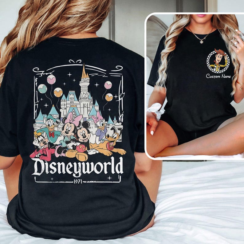 May include: Black t-shirt featuring a colorful graphic of Disney characters, including Mickey and Minnie Mouse, Donald and Daisy Duck, and Goofy, in front of a castle. The word "Disneyworld" is printed below the graphic, with "1971" underneath.