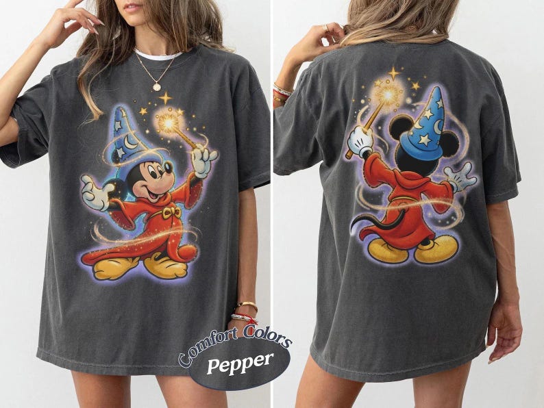 May include: A charcoal gray t-shirt featuring a graphic of Mickey Mouse as a sorcerer. The front shows Mickey facing forward in a red robe and blue star-patterned hat holding a glowing wand. The back shows the same character from behind.