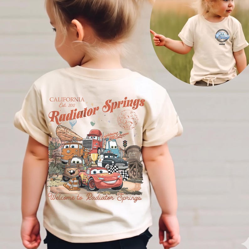 Puede incluir: Una camiseta beige de manga corta con un gr&aacute;fico colorido de personajes de la pel&iacute;cula Cars. El gr&aacute;fico incluye el texto "Radiator Springs" y "California Est. 2012". La camiseta la lleva un ni&ntilde;o peque&ntilde;o.