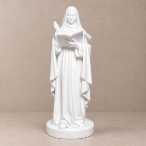 May include: A white matte statue of a figure wearing a hooded robe, holding an open book and a quill pen. The figure stands on a circular base featuring a small engraved symbol at the front, with draped fabric folds visible throughout the garment.
