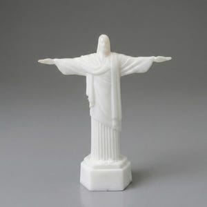 May include: A white statue of Christ the Redeemer with outstretched arms. The statue is on a white base and has a detailed design. The statue is a religious icon and a symbol of peace and hope.