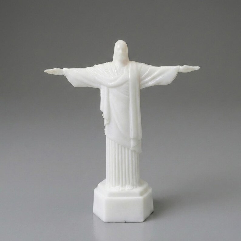 May include: A white statue of Christ the Redeemer with outstretched arms. The statue is on a white base and has a detailed design. The statue is a religious icon and a symbol of peace and hope.