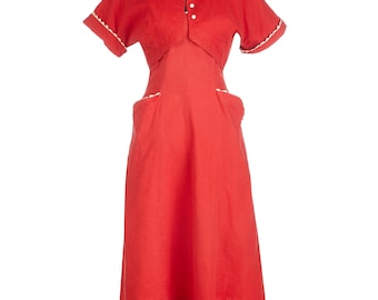 May include: A red linen dress with a white trim and a white button closure. The dress has a fitted bodice and a full skirt. It has two patch pockets on the front.