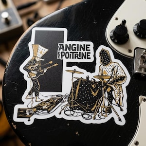 Könnte beinhalten: Zwei Aufkleber auf einer schwarzen Oberfläche. Einer zeigt einen Gitarristen, der andere einen Schlagzeuger. Beide Figuren tragen schwarz-goldene Outfits mit Punkten. Der Text "ANGINE DE POITRINE" ist ebenfalls zu sehen. Musikalisches Thema.