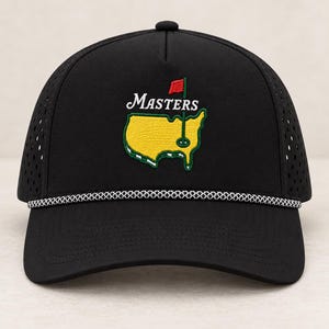 May include: A black baseball cap featuring a perforated side panel design and a white rope detail across the base of the crown. The front displays an embroidered yellow map of the United States with a red flag and the word Masters in white.