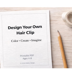 Może przedstawiać: Biała kartka papieru z napisem "Design Your Own Hair Clip" i słowami "Color • Create • Imagine". Ołówek i rolka taśmy klejącej leżą na jasnej drewnianej powierzchni. Na papierze widnieje również napis "PDF do wydruku Wiek 4-8."