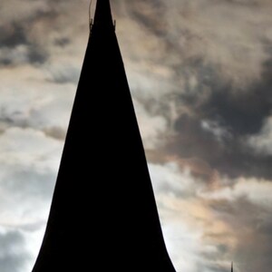 Peut inclure: Silhouette d'un clocher d'église et d'une croix sur fond de ciel nuageux. Le clocher est une forme sombre et effilée, et la croix est ornée. L'image joue sur les contrastes, avec les formes sombres sur un ciel clair et nuageux.