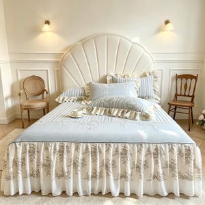 May include: A bed set featuring a light blue and white striped pattern with intricate white embroidery. The set includes a bed skirt with a floral print, matching pillows with ruffled edges, and a flat sheet, all arranged on a bed with a shell-shaped headboard.