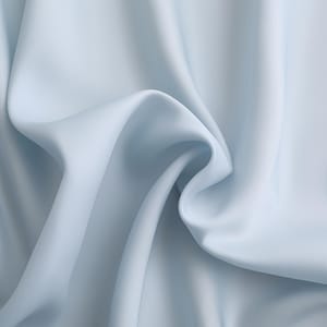 Puede incluir: Primer plano de una tela azul claro con pliegues suaves y una textura fluida. La tela parece lisa y tiene un brillo sutil, creando una sensaci&oacute;n de movimiento y profundidad. El color es un tono azul p&aacute;lido y calmante.