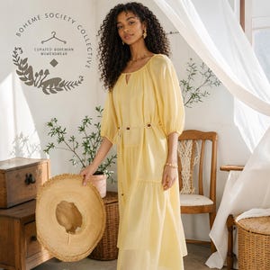 Yellow boho midi dress for women featuring lightweight Tencel fabric, romantic puff sleeves, flowing A-line silhouette, and adjustable lace-up waist detail. Feminine cottagecore summer dress with soft airy texture and relaxed fit perfect for brunch dates, vacations, garden parties, tea parties, casual chic styling, and everyday elegance. Pastoral-inspired midi dress in buttery yellow tone designed for breathable comfort and graceful movement during spring and summer wear.