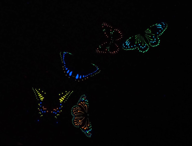 May include: A collection of four butterflies depicted in a bioluminescent style against a solid black background. Each butterfly features intricate patterns created with glowing dots and lines in vibrant shades of blue, green, orange, and red.