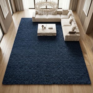 Puede incluir: Una alfombra rectangular grande de color azul marino profundo con un pelo tejido grueso y texturizado. La alfombra presenta una construcción de bucles densos y consistentes que cubre toda la superficie, proporcionando un aspecto uniforme.