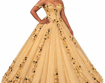 Può includere: Un abito da ballo dorato lungo fino a terra con scollo a barchetta, corpetto in stile corsetto e gonna voluminosa. L'abito è impreziosito da applicazioni floreali dorate e piccoli fiori neri al centro del motivo decorativo.