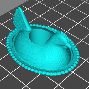 May include: A turquoise egg holder in the shape of a hen. The holder features intricate detailing, including feathers, a beak, and a beaded edge. Designed to hold one egg.