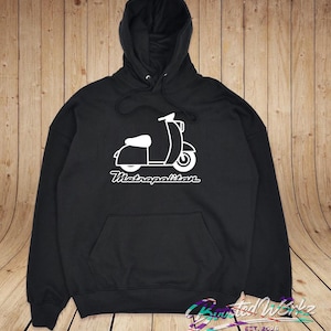 May include: Black hooded sweatshirt with a white graphic of a scooter and the word "Metropolitan" in a script font. The sweatshirt has a front pocket and a drawstring hood. The design is centered on the chest.