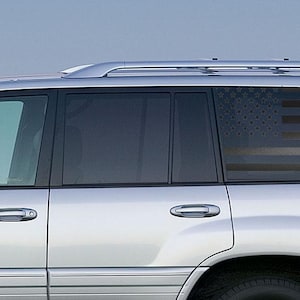 Puede incluir: SUV plateado con una ventana trasera tintada que presenta un diseño de bandera estadounidense en negro y gris. El vehículo tiene una baca y un alerón trasero. El texto "Boosted Obriz" es visible en el lateral.