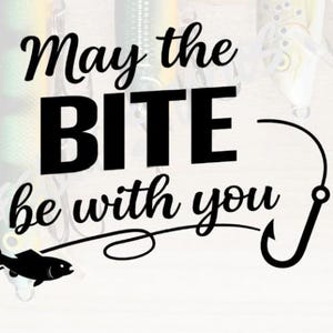 以下が含まれることがあります： 「May the BITE be with you」のテキストが入った白黒グラフィック。 釣り針と魚のシルエットもデザインに含まれています。 背景にはルアーがあります。