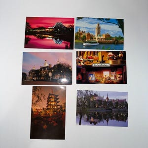 May include: A collection of six vintage postcards featuring various scenic views. The postcards showcase architectural landmarks, landscapes, and attractions, with vibrant colors and detailed imagery. The postcards are arranged on a white surface.