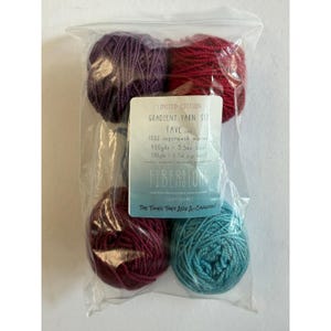 May include: A clear plastic bag containing four balls of yarn in purple, red, dark pink, and teal. A label reads: LIMITED EDITION GRADIENT YARN SET FAVE 100% superwash merino 400yds 3.5oz total (80yds 0.7oz per mini) FIBERSTORM THE TIMES THEY ARE A-CHANGIN'.