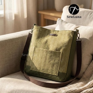May include: Olive green tote bag with a brown shoulder strap and a front pocket. The bag has a vertical striped pattern and a small leather tag. The bag is sitting on a beige sofa. The brand name "SewLuna" is visible.