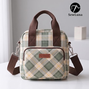 Peut inclure: Un sac fourre-tout de forme carrée avec un motif à carreaux vert, crème et jaune, doté de poignées en sangle marron et d'une bandoulière amovible. L'avant comporte une poche zippée avec une étiquette rectangulaire marron marquée "handmade".