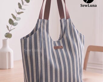 May include: A blue and white striped tote bag with brown handles. The bag has a rectangular shape with a wide opening and a small leather tag that says "handmade". The bag is sitting on a wooden table.