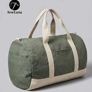 Minimalist earthy green and beige canvas duffle bag sewing pattern PDF with sturdy webbing handles and a side pocket, displayed against a light grey background. Perfect weekender bag sewing project.