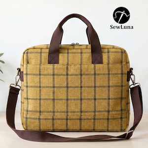 Mustard yellow plaid handmade laptop bag sewing pattern featuring brown webbing handles, an adjustable shoulder strap, a top zipper, and a front flap pocket, displayed on a clean white background.