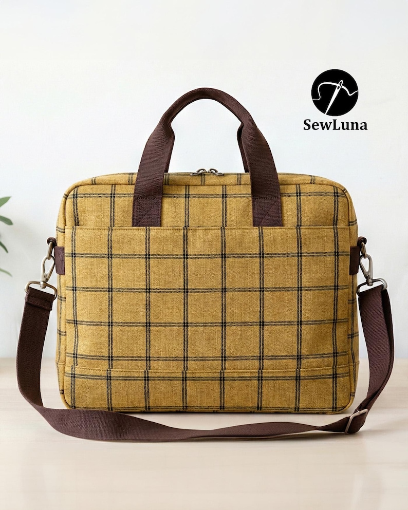 Mustard yellow plaid handmade laptop bag sewing pattern featuring brown webbing handles, an adjustable shoulder strap, a top zipper, and a front flap pocket, displayed on a clean white background.