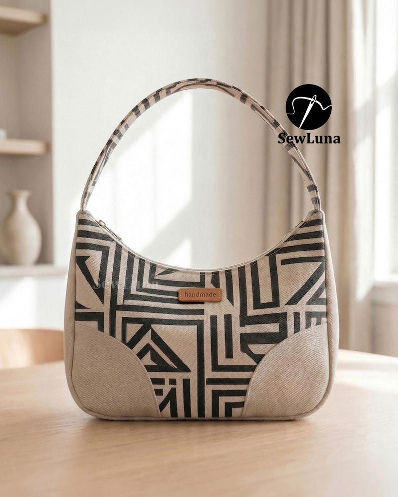 A handmade geometric patterned shoulder bag sitting on a marble table next to a coffee cup and sunglasses. Showcasing the finished result of the Avery shoulder bag PDF sewing pattern with a curved silhouette and top zipper closure.