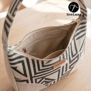 Puede incluir: Una taza de cer&aacute;mica blanca con asa negra y el texto "But First, Coffee" en negrita negra. La taza est&aacute; sobre un fondo borroso, sugiriendo un ambiente acogedor. La taza mide aproximadamente 10 cm de alto.