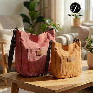 Puede incluir: Dos bolsos de hombro de lona en tonos rojos y dorados sobre una mesa de madera. Cada bolso tiene un bolsillo frontal y una correa marrón. Los bolsos tienen una etiqueta "handmade" y la marca "SewLuna" es visible.