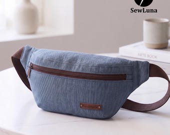 Puede incluir: Una riñonera azul con cierre de cremallera marrón y una correa ajustable marrón. El bolso tiene una pequeña etiqueta rectangular marrón en la parte delantera con la palabra handmade impresa en blanco. El diseño incluye una cremallera superior.
