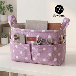 Purple polka dot handmade fabric purse organizer bag filled with daily essentials like a hairbrush, hand cream, and keys. A PDF sewing pattern project for a bag insert or desk storage bin displayed on a clean white background.