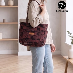 May include: A tote bag featuring a dark maroon and black geometric pattern with a repeating cube design. The bag has a light beige upper section, brown shoulder straps, and a front pocket with a small rectangular label reading SewLuna.
