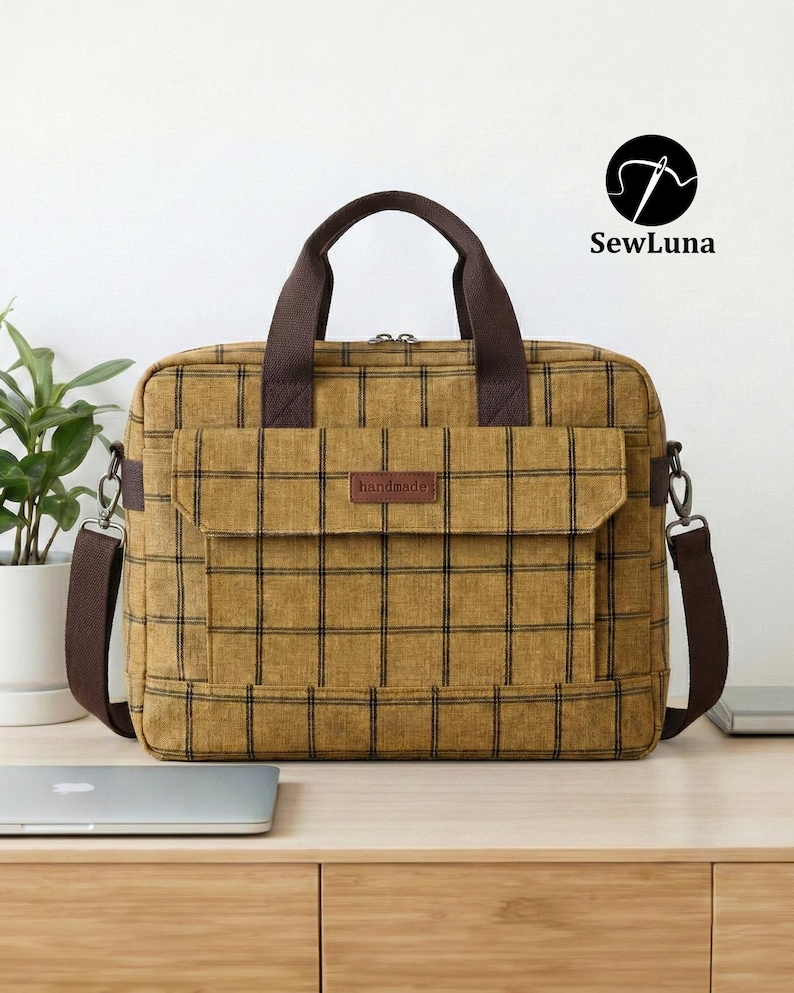Mustard yellow plaid handmade laptop bag sewing pattern featuring brown webbing handles, an adjustable shoulder strap, a top zipper, and a front flap pocket, displayed on a clean white background.