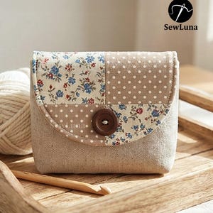 May include: A small, square fabric pouch with a flap closure. The flap is divided into two sections: one with a floral pattern of blue and red flowers, and the other with white polka dots on a tan background. A brown button secures the flap. The pouch is on a wooden tray.