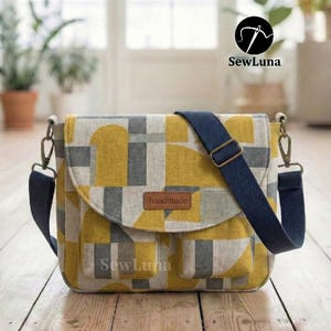 May include: A handmade messenger bag with a geometric pattern in yellow, gray, and white. It features a navy blue adjustable strap and a leather tag that says "handmade". The bag has a flap closure and two front pockets. The brand name "SewLuna" is visible.