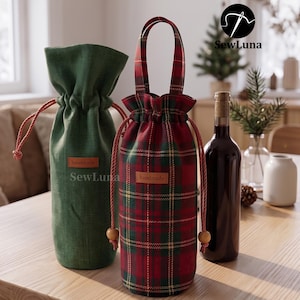 May include: Two fabric wine bottle bags with drawstring closures. One bag is solid dark green, the other features a red and green plaid pattern. Both have a brown rectangular tag labeled handmade and the text SewLuna.