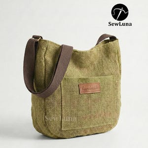 May include: Olive green burlap tote bag with a brown shoulder strap and a front pocket. The bag features a brown leather patch that reads "handmade". The SewLuna logo is in the upper right corner.