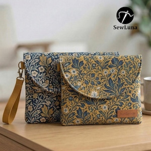 May include: Two floral patterned pouches with a mustard yellow wrist strap and a small leather tag that says "handmade". The pouches have a navy blue and gold floral design. The brand name "SewLuna" is visible in the upper right corner.