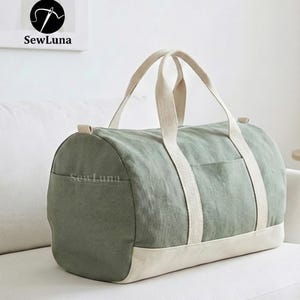 Minimalist earthy green and beige canvas duffle bag sewing pattern PDF with sturdy webbing handles and a side pocket, displayed against a light grey background. Perfect weekender bag sewing project.