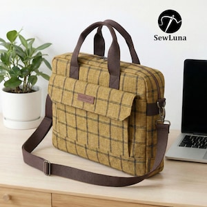 Mustard yellow plaid handmade laptop bag sewing pattern featuring brown webbing handles, an adjustable shoulder strap, a top zipper, and a front flap pocket, displayed on a clean white background.